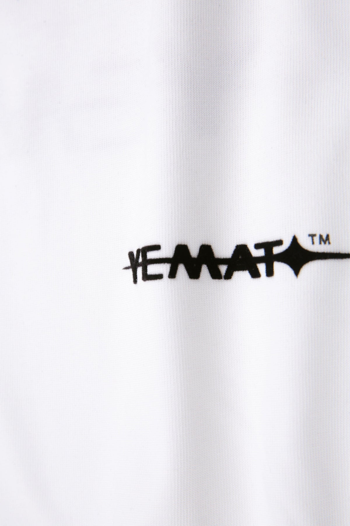 YEMAT Velvet Tee White — macro detail of raised velvet logo and cotton texture